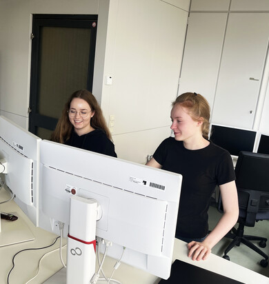 Zwei Auszubildende sitzen am PC-Arbeitsplatz hinter Monitoren